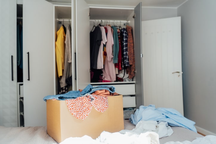 cardboard box full of clothing with open closet doors in the background