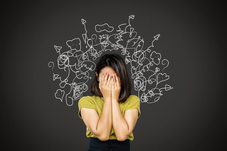 a woman covers her face in distress with squiggles and chaotic lines drawn around her head