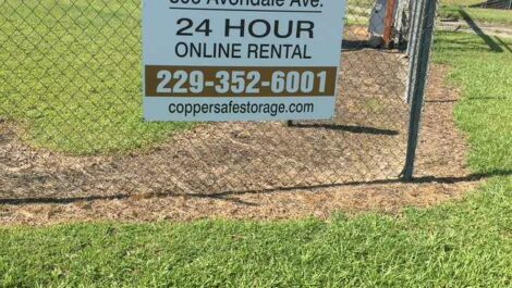 Sign on fence 24 hour online rental 229-352-6001 coppersafestorage.com in Tifton, GA.