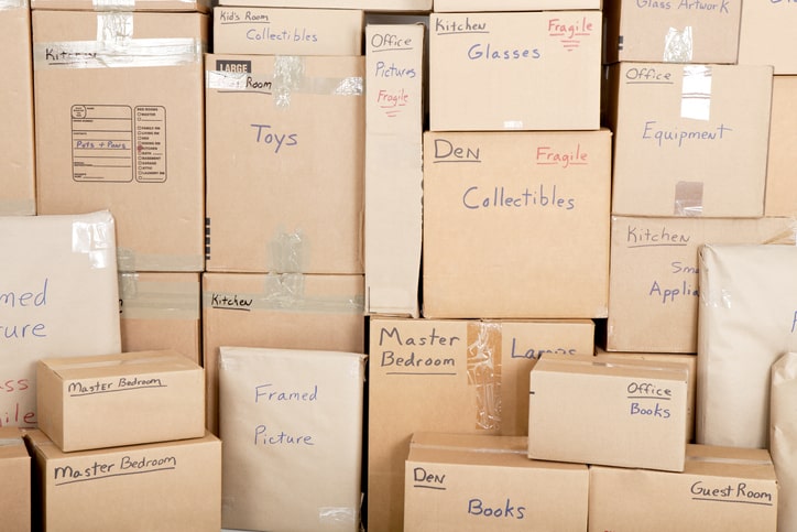 Stacked brown boxes have been written on to indicate their contents and where they belong.