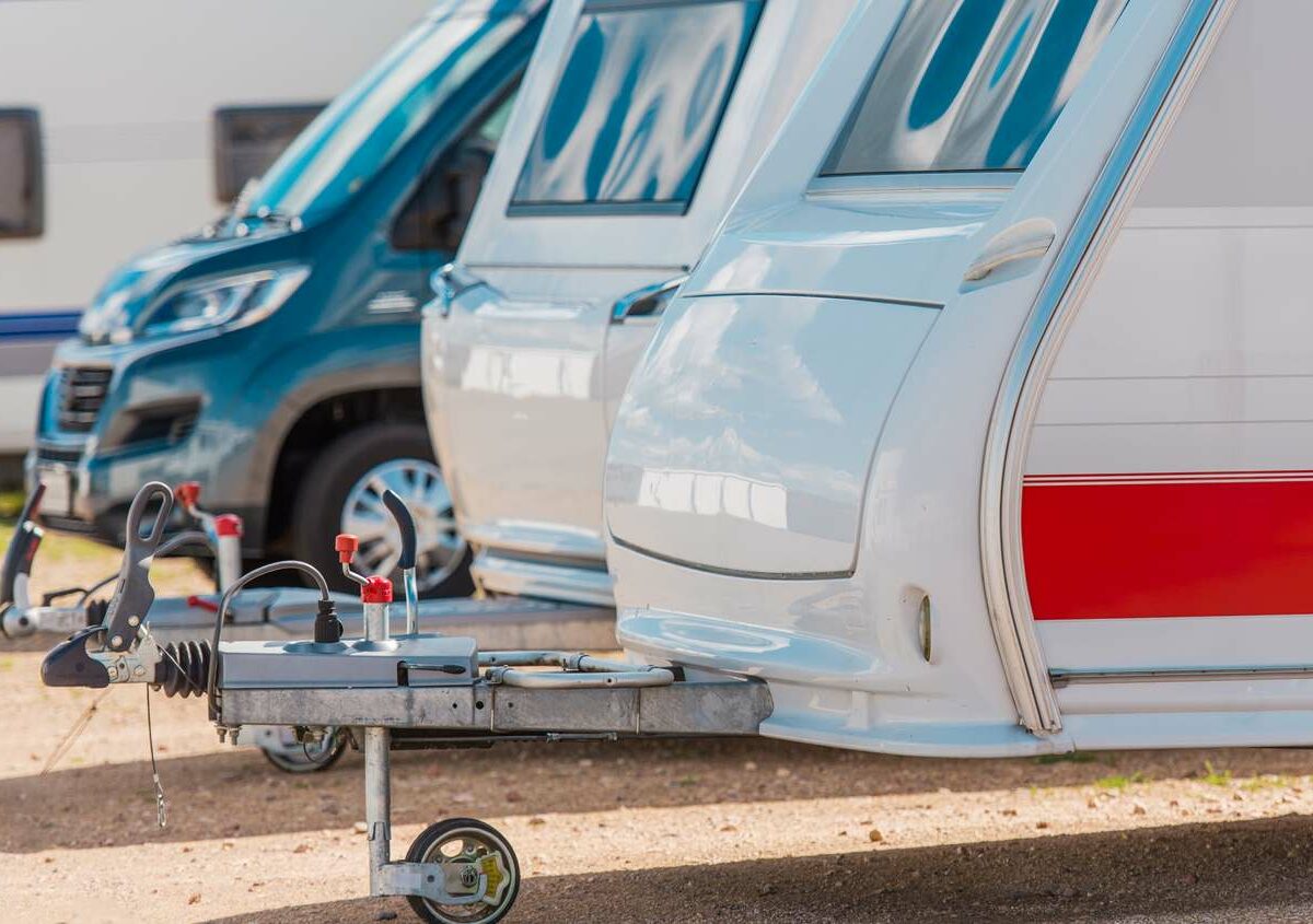 A set of RV's parked outside next to a car.