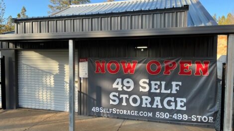 49 Self Storage sign that says "Now Open" in front of a storage unit.