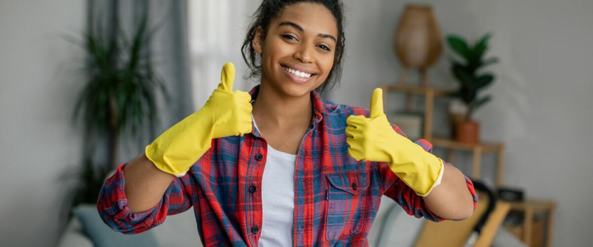 A woman with cleaning gloves giving two thumbs up to the camera