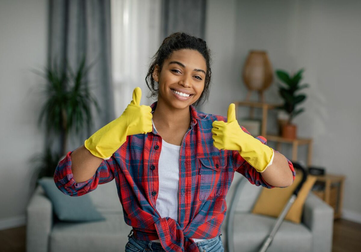 A woman with cleaning gloves giving two thumbs up to the camera