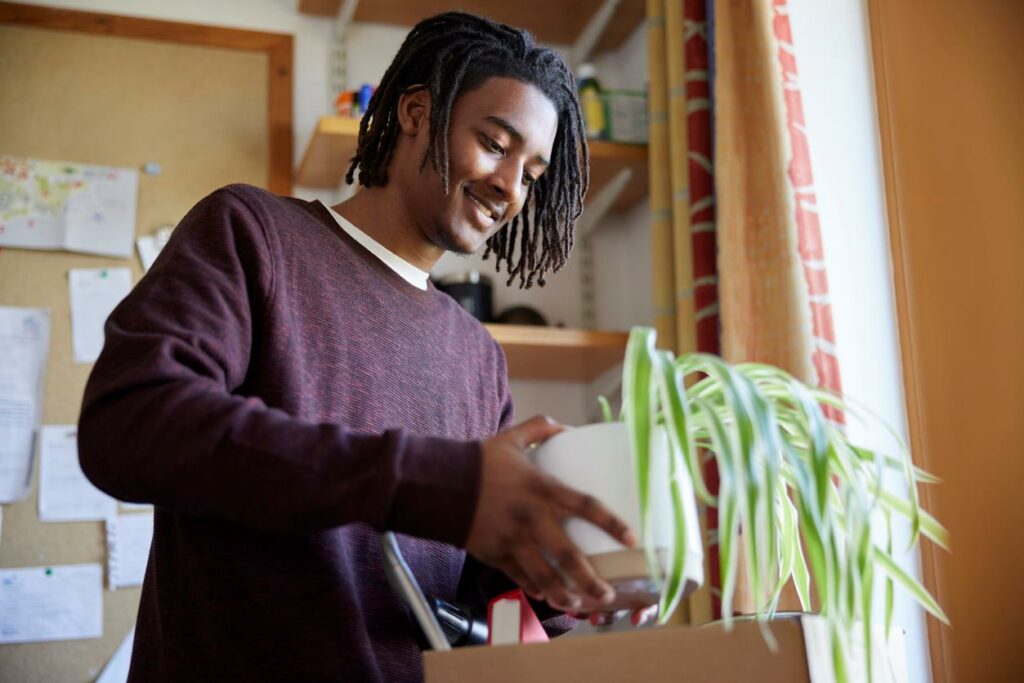 A man packing away a plant into a moving box