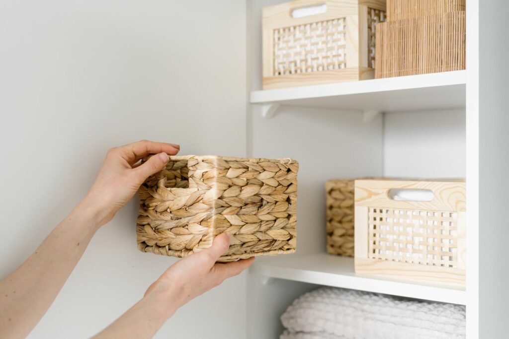 Some placing a whicker basket on an organized shelf