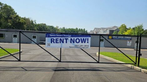 Entry gate with Rent Now banner attached at Space Savers Storage in Mobile, AL.