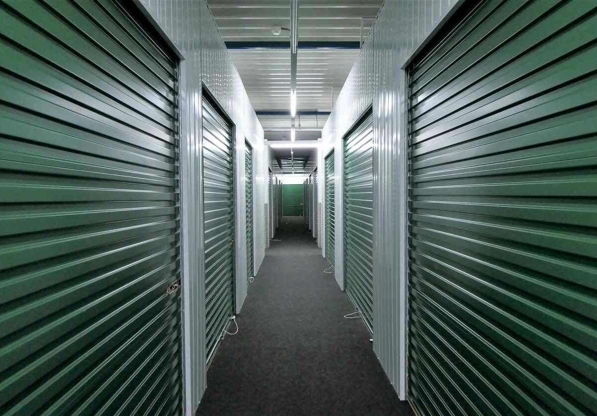 A series of green storage unit doors lining a hallway