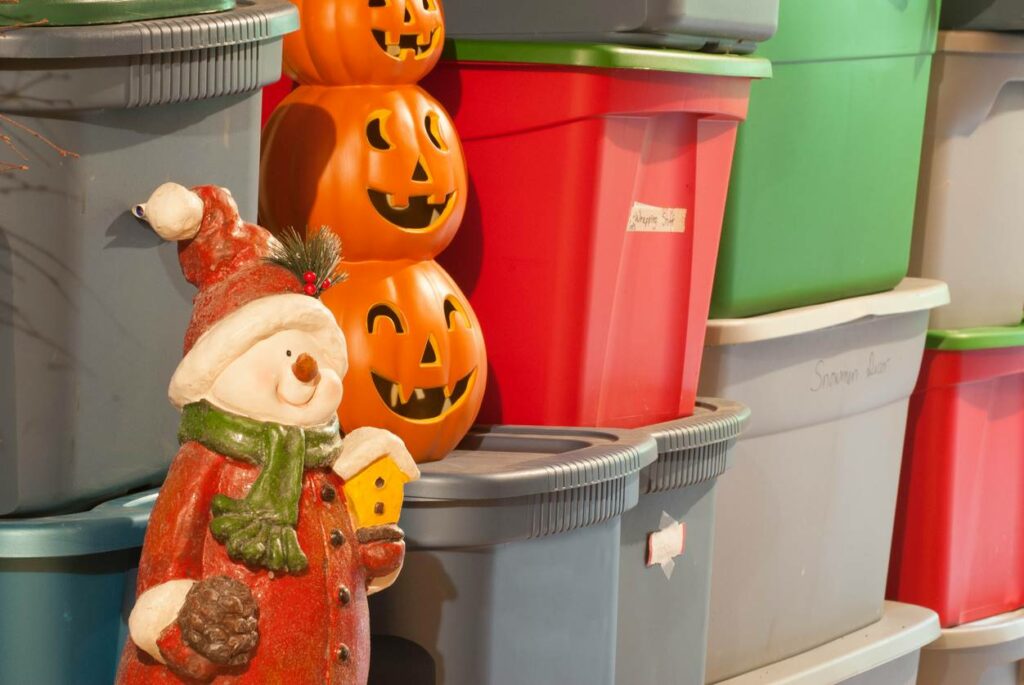 Pumpkins and a small santa claus stores in a storage unit along with extra tubs.