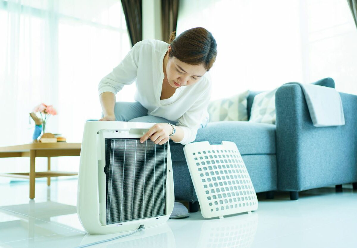 Woman changing air purifier filter as a part of spring cleaning.