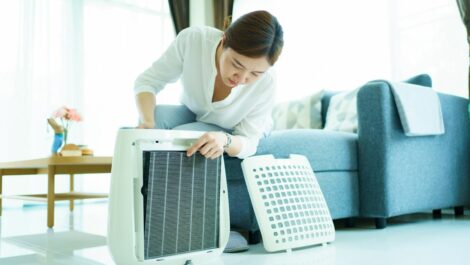 Woman changing air purifier filter as a part of spring cleaning.