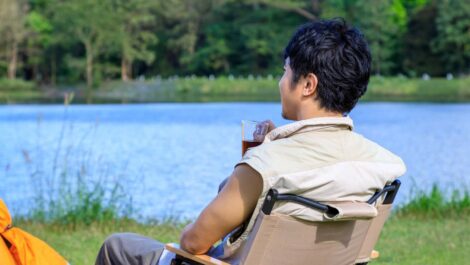 Man relaxing in a chair and drinking coffee near the lake.