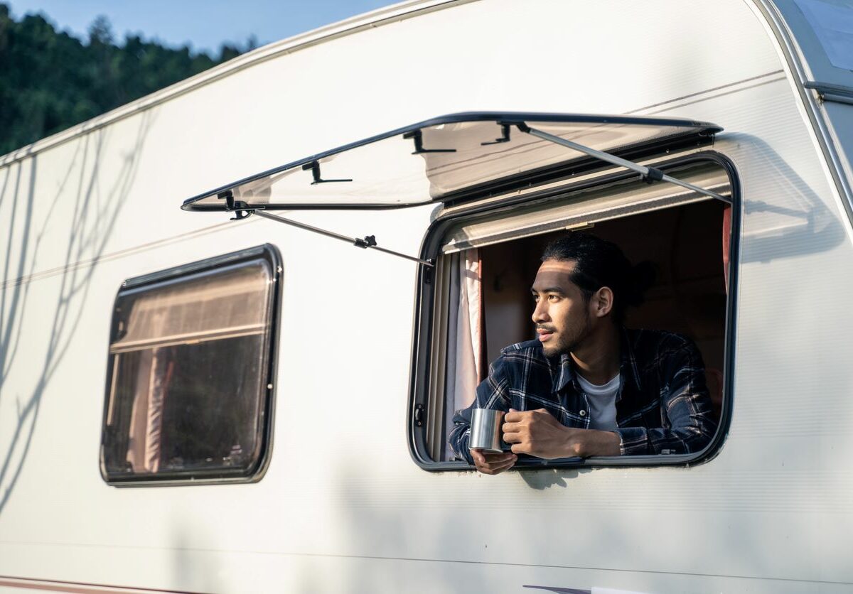 Man looking outside of his RV window, ready for a road trip.