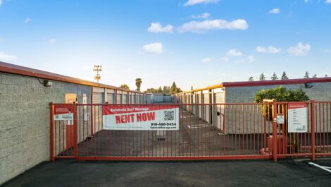 Storage facility with security gate and a "Rent Now" Banner on it.