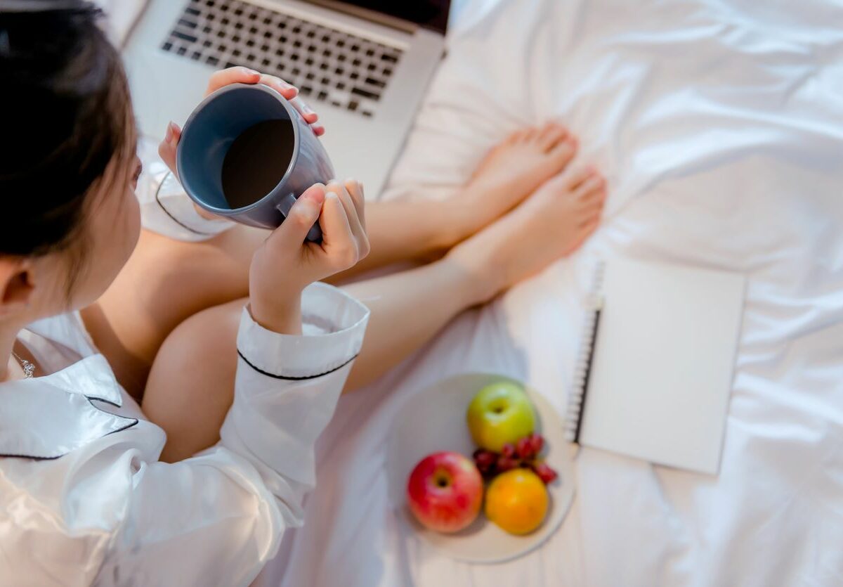 Young woman eating fruits and drinking tea while journaling.