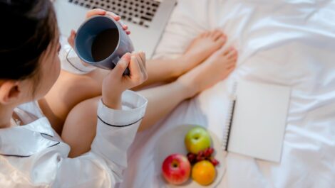 Young woman eating fruits and drinking tea while journaling.