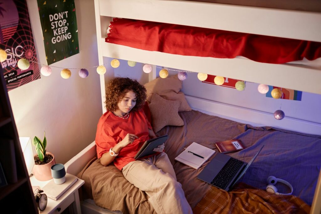 Student is working on homework on her bunk bed.