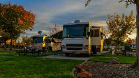 Two RVs parked at a campsite during autumn at sunset.