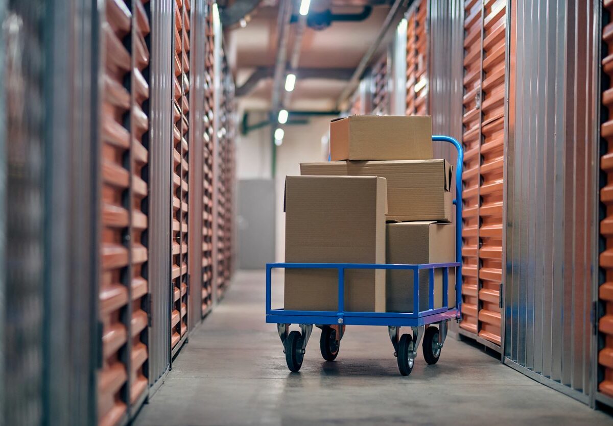 A cart of boxes in the hallway of a storage facility surrounded by orange storage unit doors