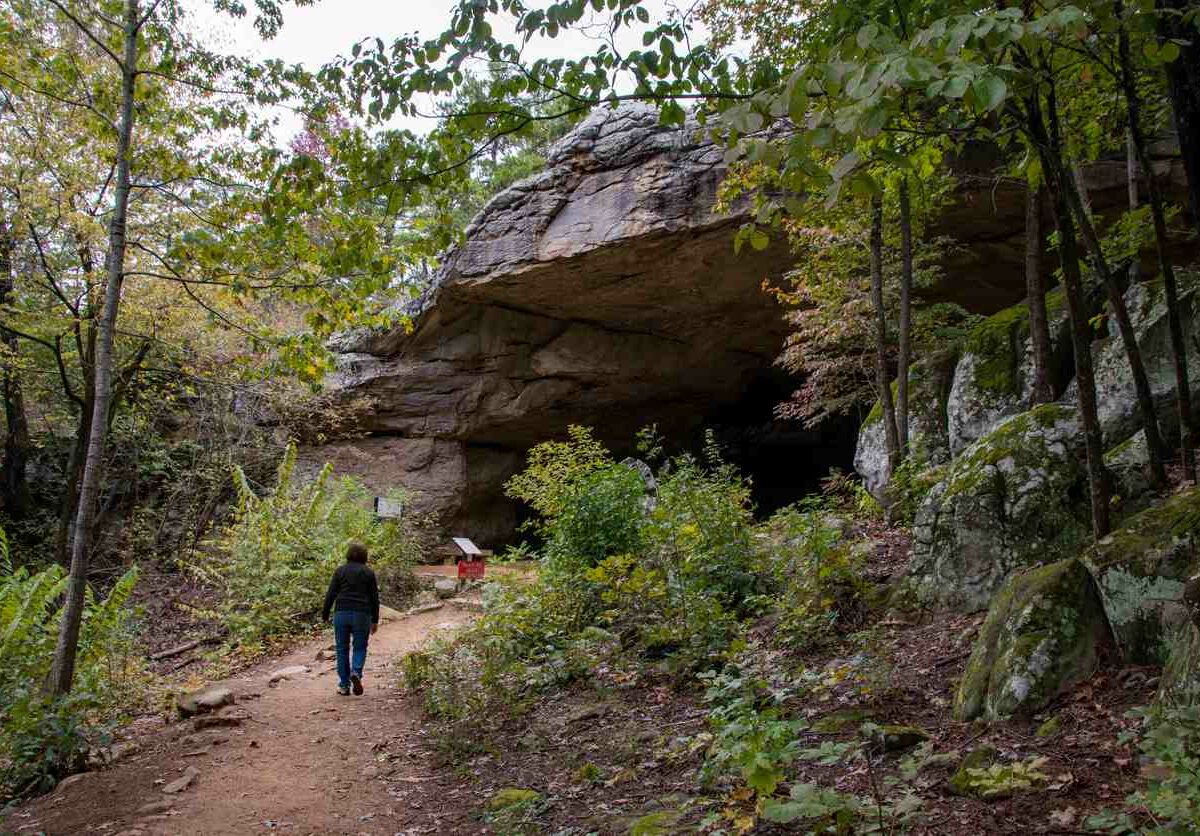 A woman walking toward the cave in Petit Jean State Park