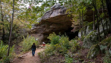 A woman walking toward the cave in Petit Jean State Park