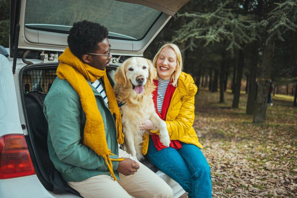 A young couple getting ready to go out on a scenic drive with their dog.