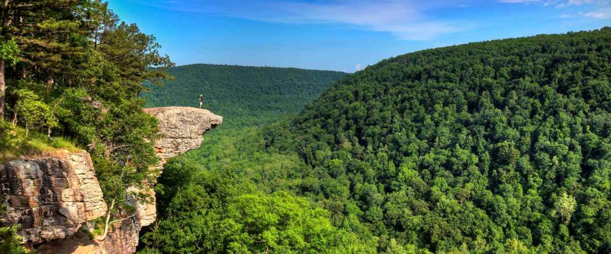 A hiker enjoying the view on a cliff above the Ozark National Forest.