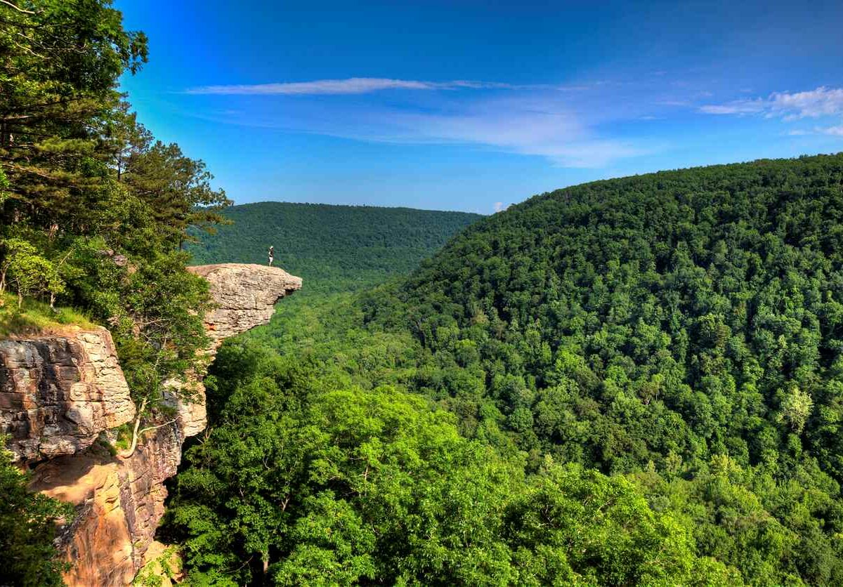 A hiker enjoying the view on a cliff above the Ozark National Forest.