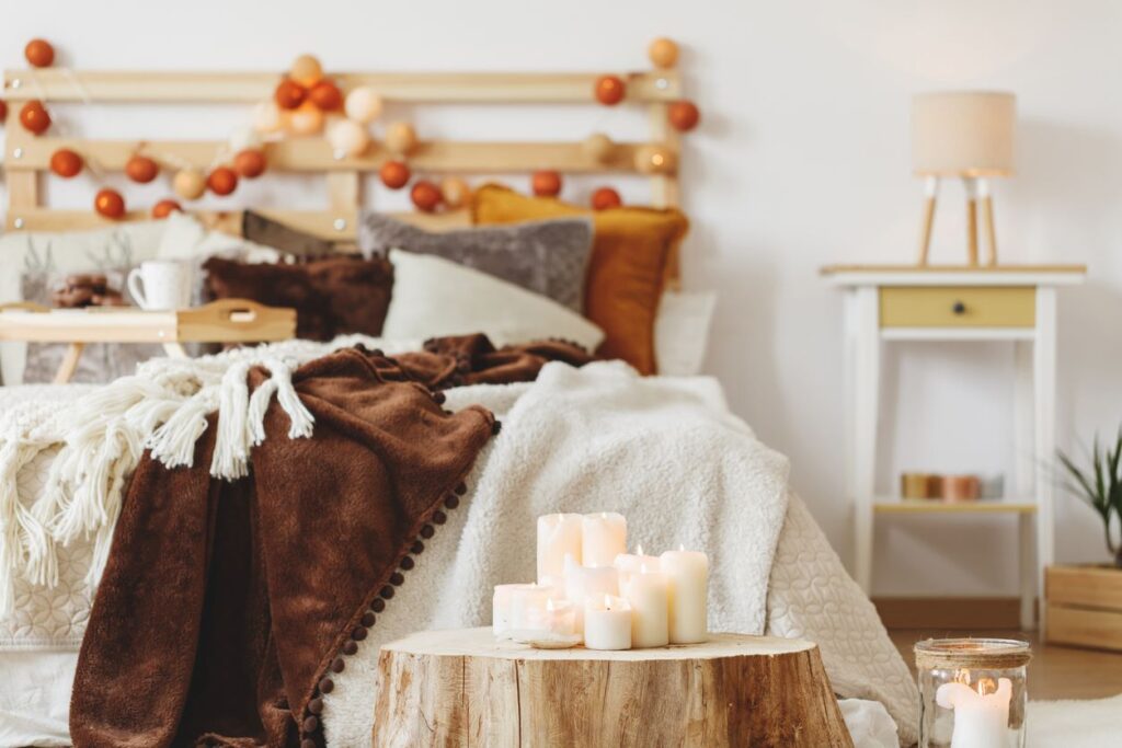 A white-walled bedroom decorated with brown and cream blankets and orange garlands for fall.