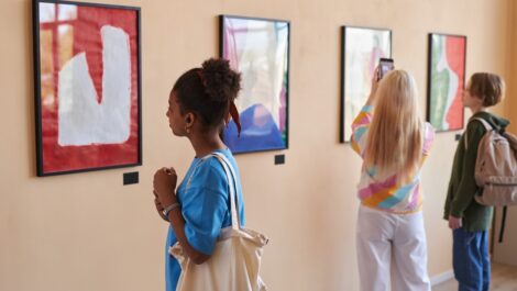 Visitors admire abstract paintings in a brightly lit art gallery.