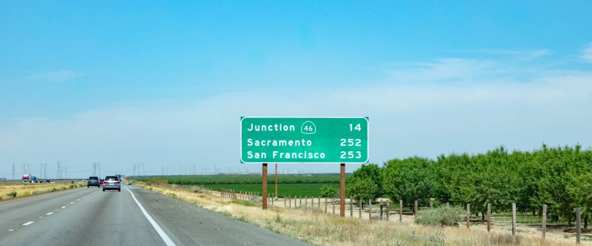 Cars driving on a highway with a road sign showing distances to Junction 46, Sacramento, and San Francisco.