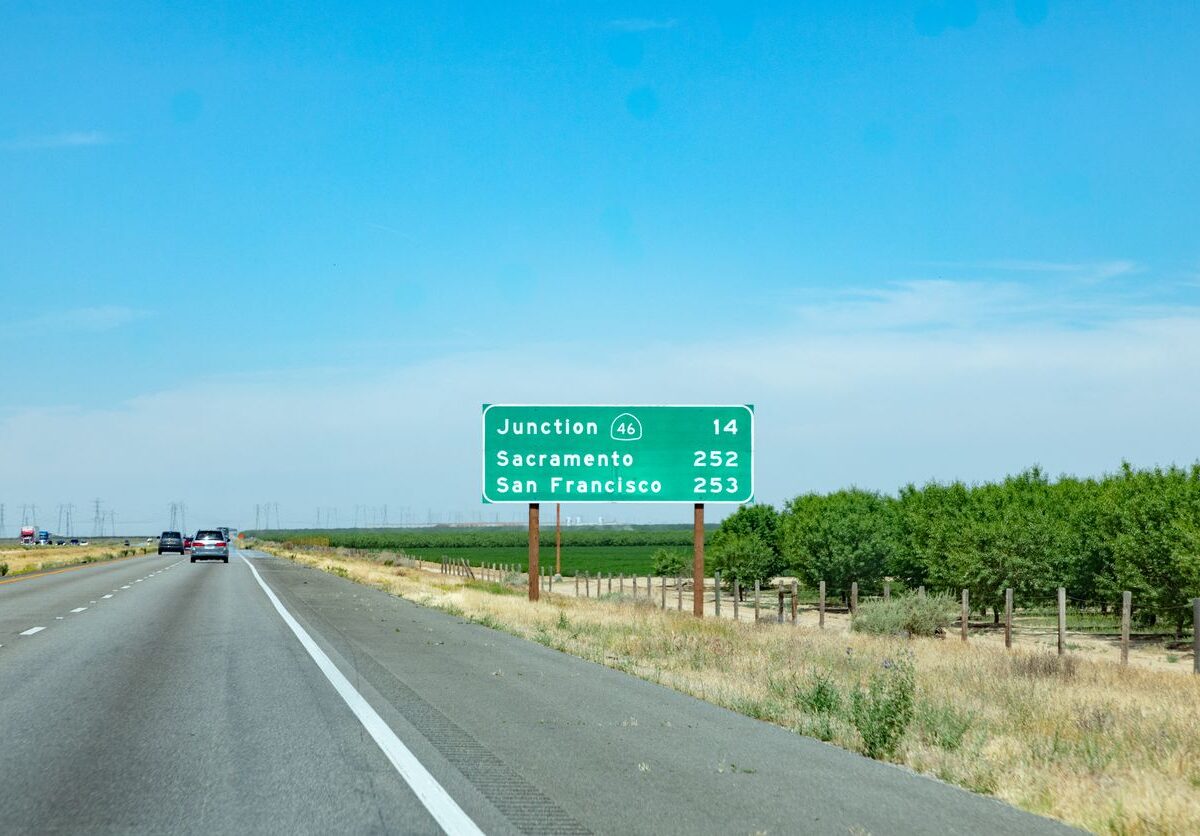 Cars driving on a highway with a road sign showing distances to Junction 46, Sacramento, and San Francisco.