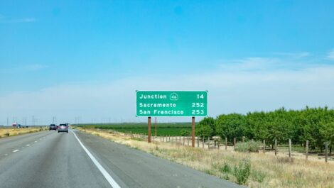 Cars driving on a highway with a road sign showing distances to Junction 46, Sacramento, and San Francisco.