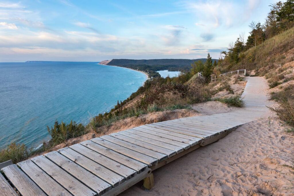 A wooden boardwalk winds through sandy dunes overlooking Lake Michigan at Sleeping Bear Dunes National Lakeshore