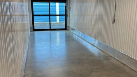 Outdoor storage units at State College Storage facility with pitched roofs and wide gravel aisles, with a blue sky and clouds overhead.