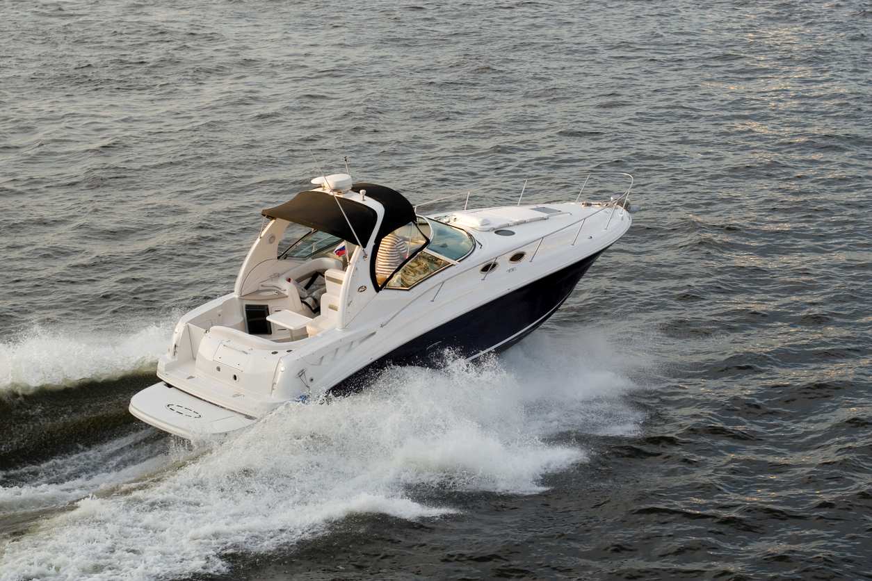 A sleek white motorboat with a black canopy speeds across the water.