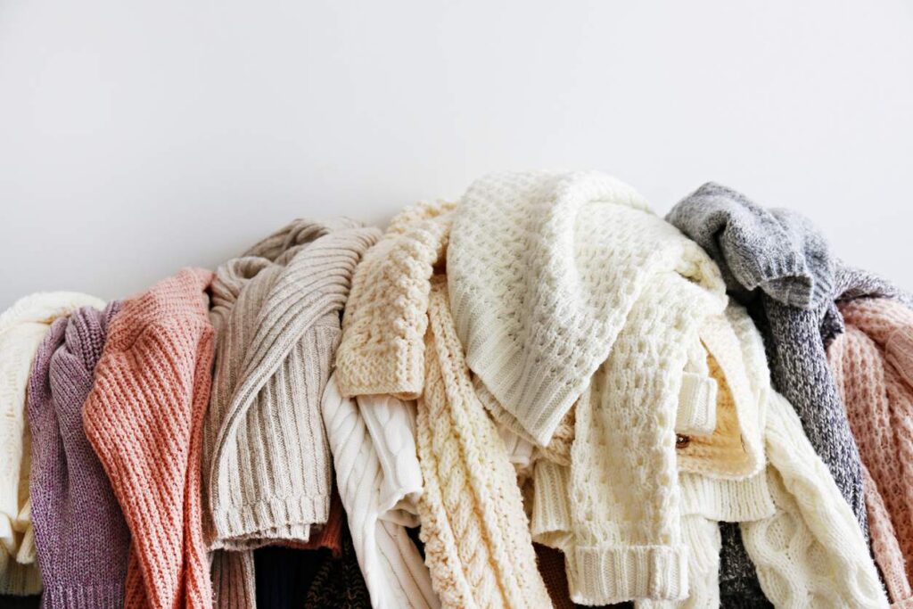 A pile of warm sweaters just taken out of storage. They come in different colors.