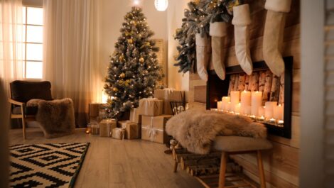 Festive living room decorated with a Christmas tree with gifts underneath and a fireplace with stockings.