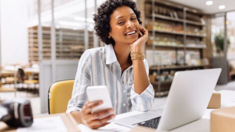 Successful online store owner smiling at the camera in a warehouse